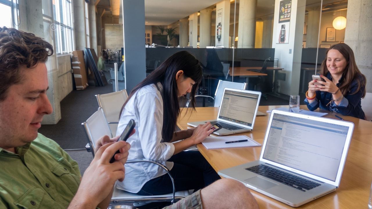 Team members play testing game concepts on phones around a conference table